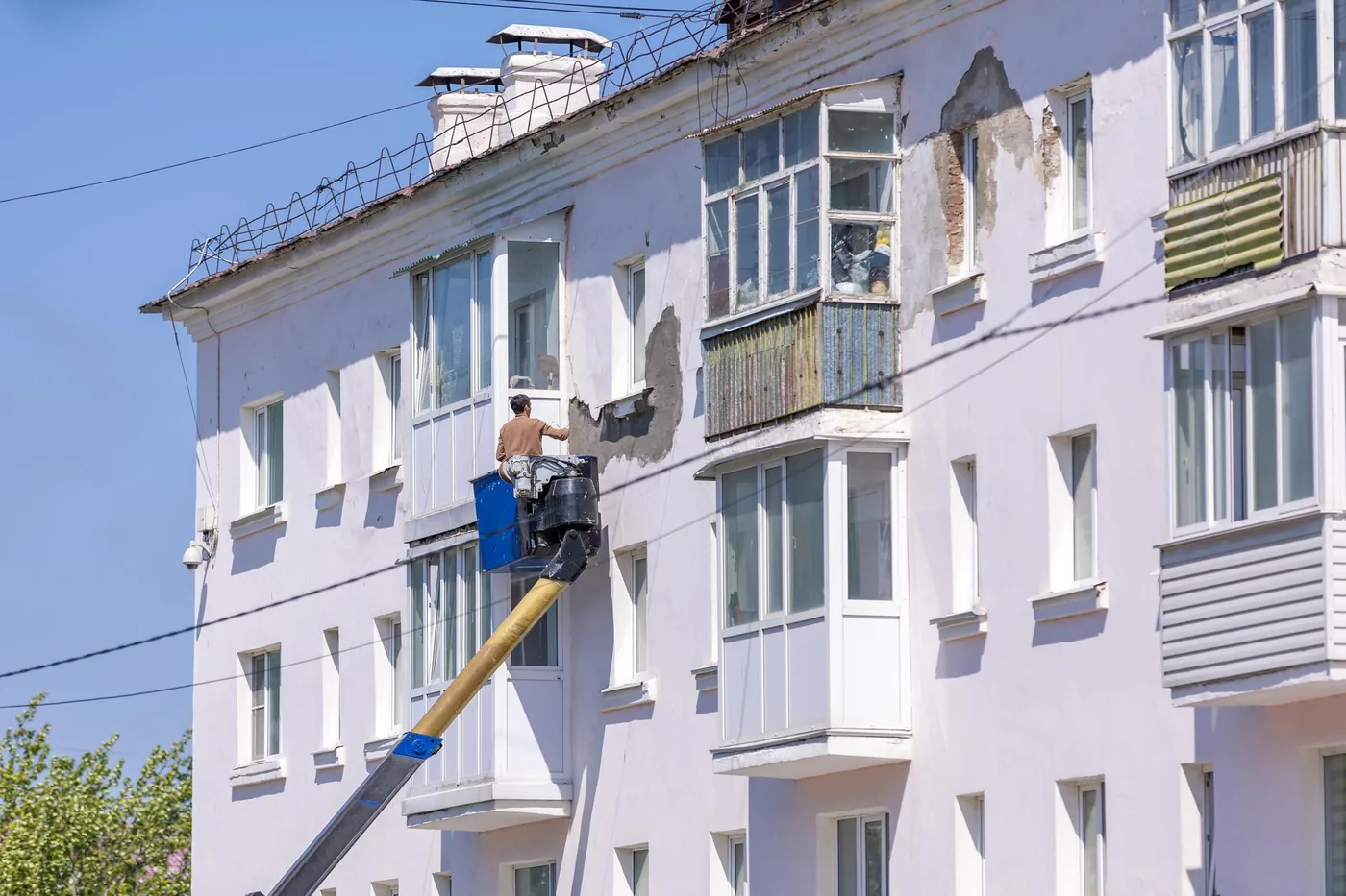 dělník opravuje fasádu domu z plošiny