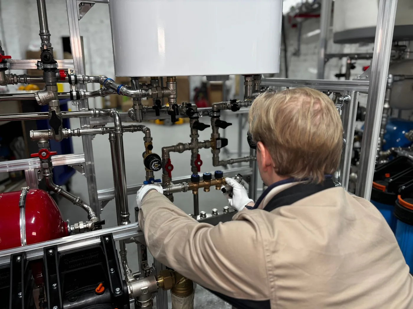 technik seřizuje topný rozvaděč s potrubím