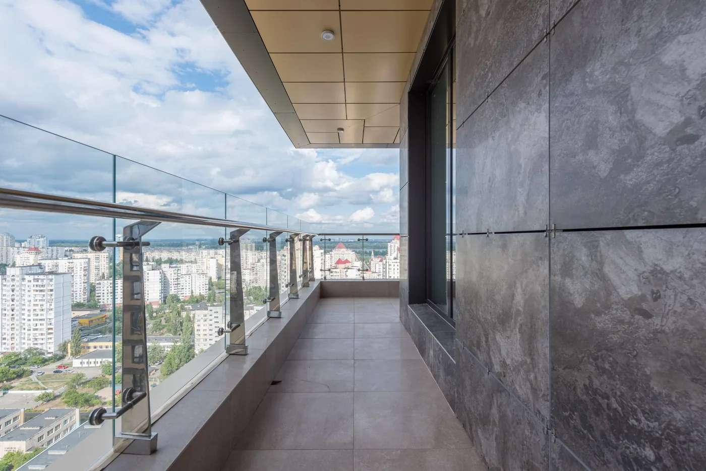 balkon s dlažbou a skleněným zábradlím