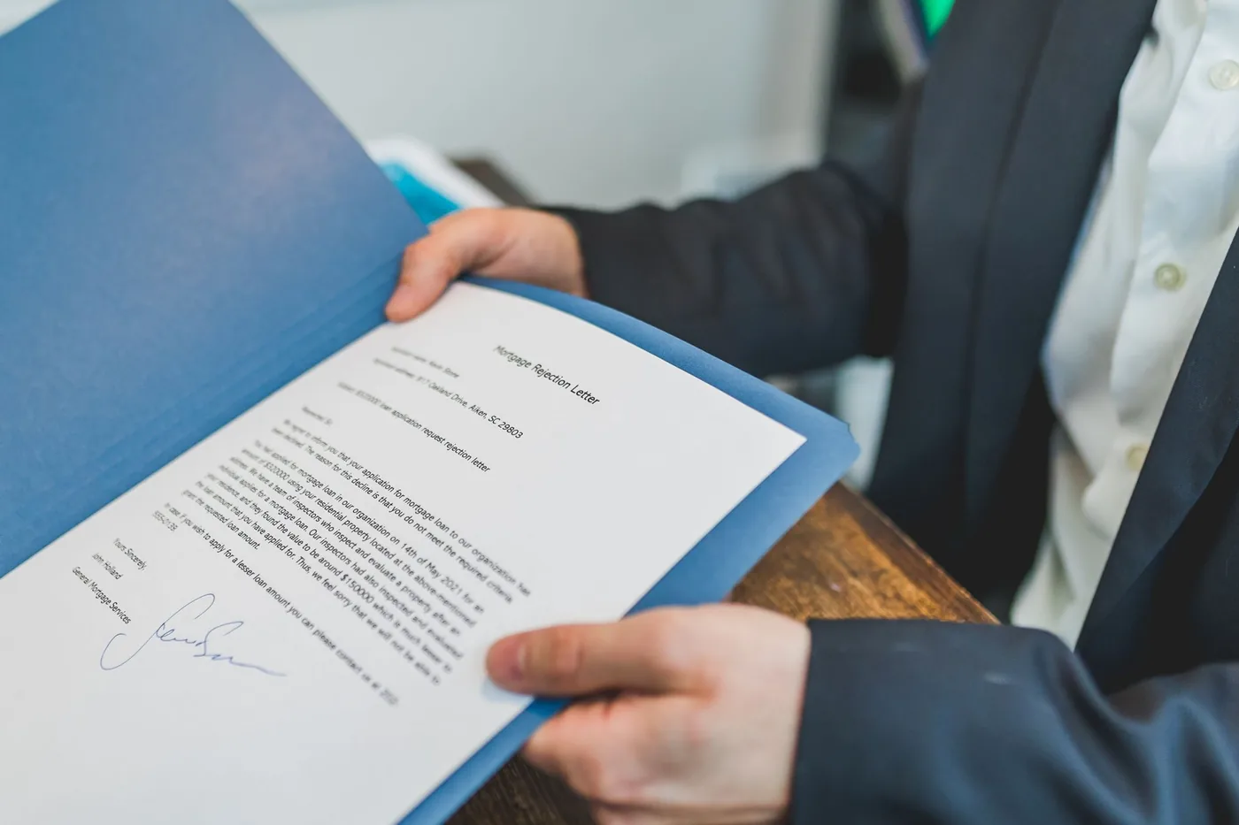 muž v obleku ukazuje podepsaný dokument