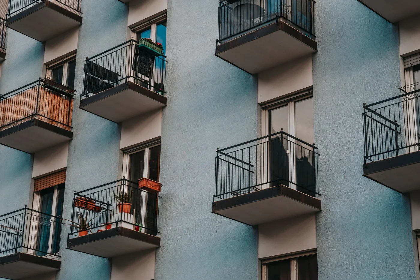 modrý bytový dům s černým zábradlím na balkonech