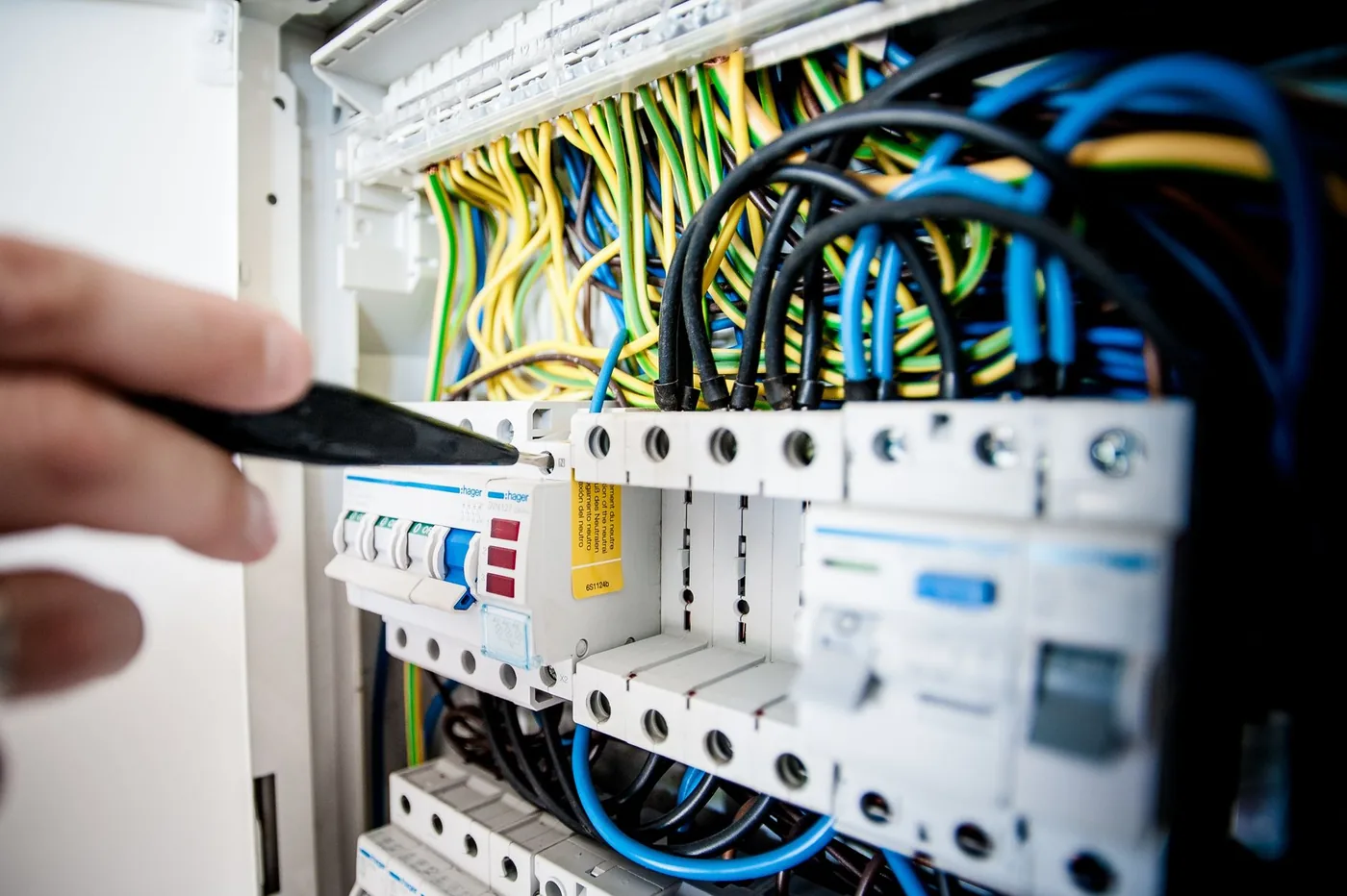 ruka elektrikáře u rozvaděče s vodiči