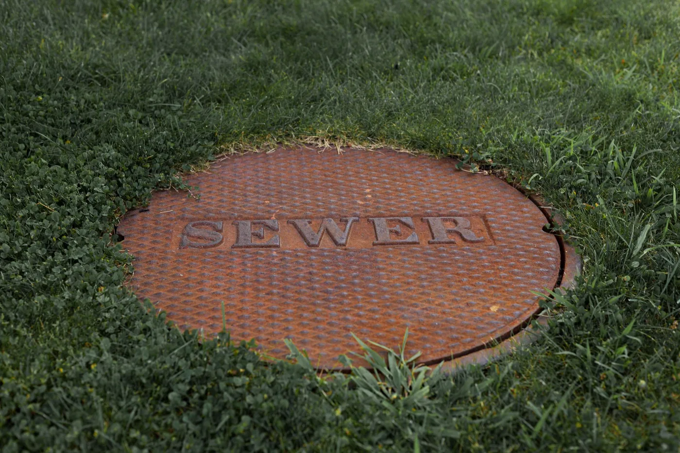 poklop kanalizace zapuštěný v trávníku